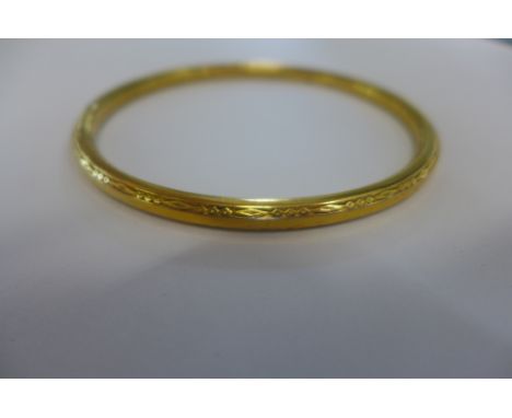 A gilt metal bangle, tests to approx 9ct, approx 11.8 grams, 8.5cm in diameter 