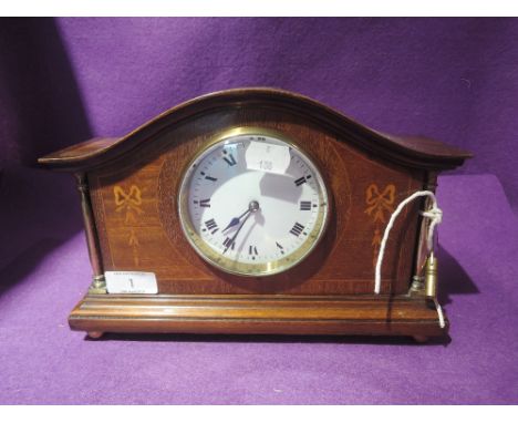 A mantle clock with veneer inlay frontage enamel face and brass column supports