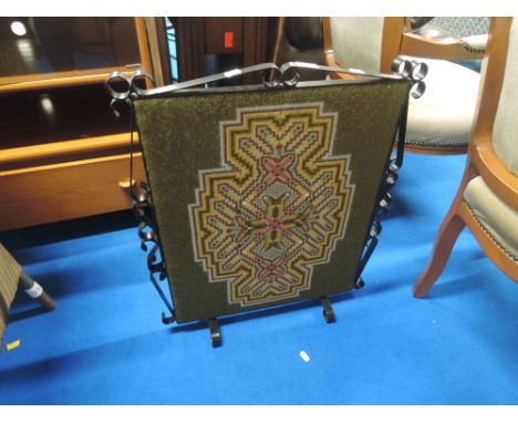 A wrought iron frame woolwork firescreen 