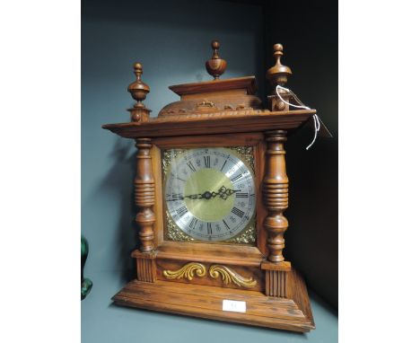 A bracket mounted clock with column design and brass face battery operated
