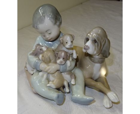 A Lladro Group of a child holding a group of puppies.