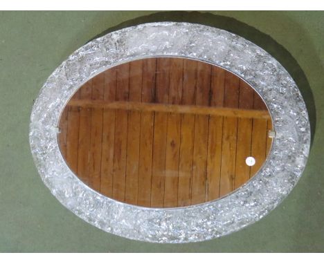 An oval mirror with illuminating lucite surround 