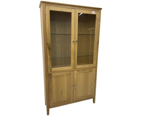 Contemporary light oak display cabinet on cupboard, fitted with two glazed doors enclosing two adjustable glass shelves with 