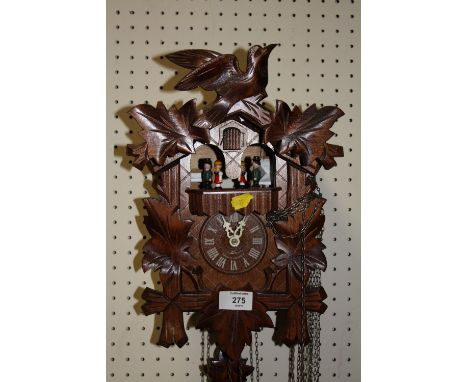 A GERMAN CARVED BLACK FOREST STYLE CUCKOO CLOCK WITH PENDULUM AND WEIGHTS 