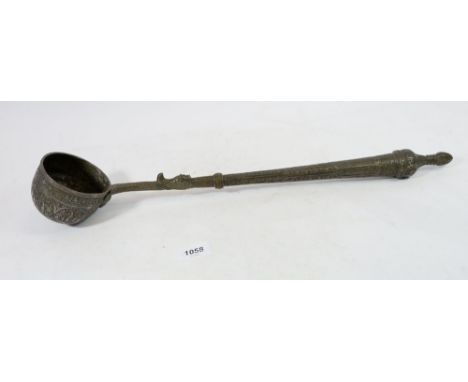 An Islamic metal ladle engraved with decorative text 