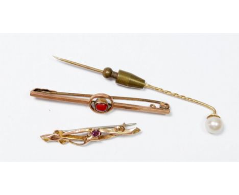 A 9 carat gold bar brooch set red stone, a gold scrollwork brooch (unmarked) and a yellow metal stick pin set pearl 