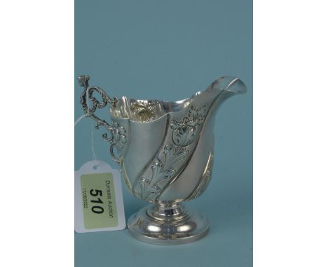 A silver cream jug with embossed floral decoration, female bust to handle on pedestal base (light push), hallmarked Birmingha