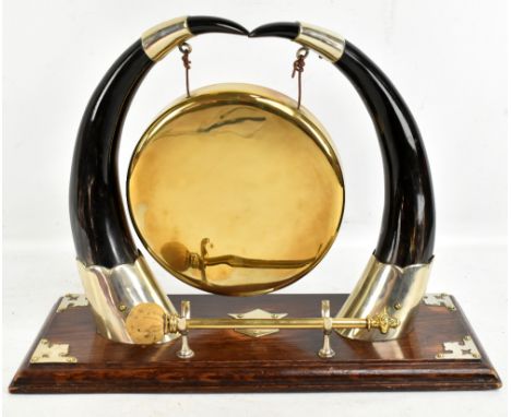 An early 20th century table gong, raised on two horns with silver plated mounts, terminating on a rectangular oak plinth base