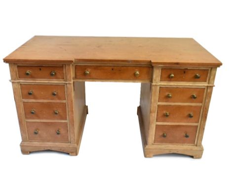 A pine nine drawer inverted breakfront knee hole desk with brass knock handles on a bracket plinth base, width 129cm, height 