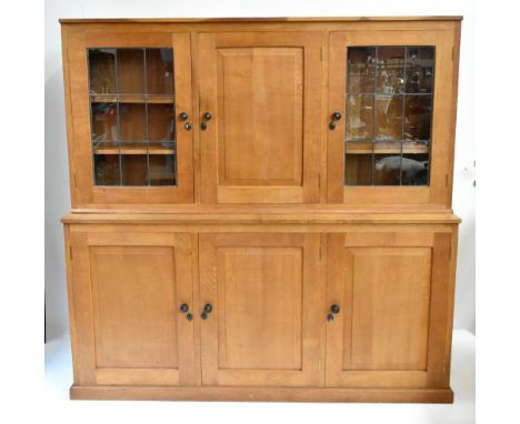 DEREK 'LIZARDMAN' SLATER; a light oak bookcase, the upper section with central panelled cupboard door flanked by two lead gla