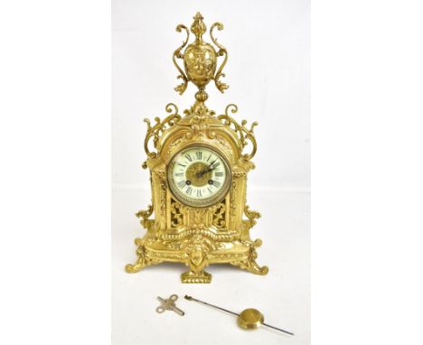 A late 19th century French gilt metal Rococo-style eight day mantel clock, the pierced case with urn finial and applied and c