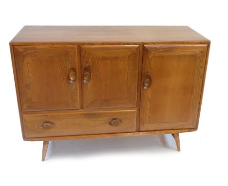 ERCOL; a medium elm sideboard with three panelled doors and single base drawer, raised on column supports, height 81.5cm, len