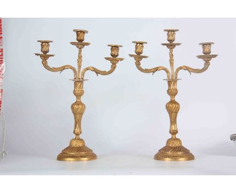 A PAIR OF 19TH CENTURY ORMOLU THREE BRANCH CANDELABRA with twisted rococo style stems on circular bases; having lift out leaf