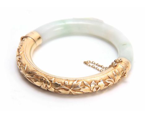 AN ORIENTAL HALF HINGED JADE AND SILVER GILT BANGLE with embossed designs of leafage and flower heads 8cm diameter