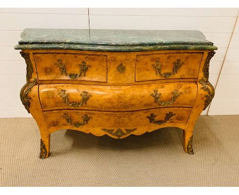 A continental birds eye maple serpentine bombe commode applied with gilt bronze mounts and green marble top
