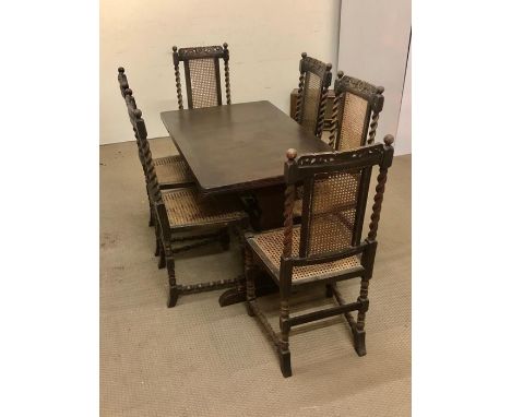 A dark oak extendable dining table with six matching dining chairs with cane seating and back barley twist side detailing and