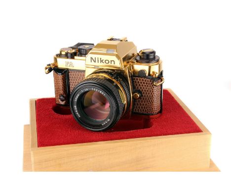 A Nikon FA Gold ‘Grand Prix ‘84’ SLR Camera, gold, serial no. 2005022, with AIS f/1.4 50mm lens, gold, serial no. 5521831, bo