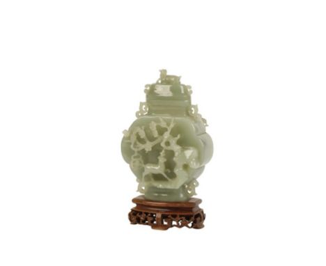 CHINESE CELADON JADE VASE of flattened baluster form, the domed cover with a clear finial, the sides carved in high relief wi