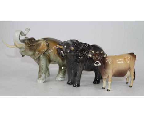A Royal Dux figure of an elephant shown standing with trunk raised, height 14cm (a/f), together with a Beswick pottery figure