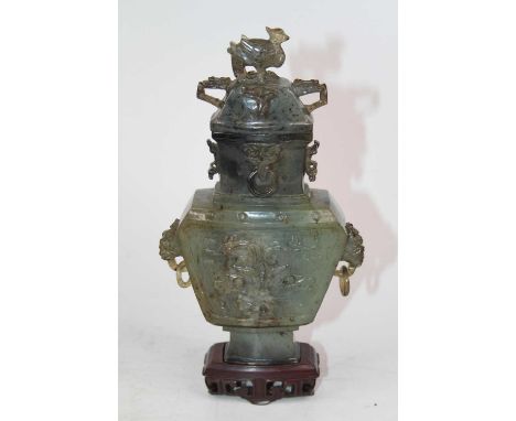 A Chinese carved hardstone urn and cover, the lid surmounted by a mythical bird, the urn flanked with dragon handles on hardw