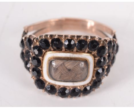 A George III gold mourning ring set a central panel of plaited hair within white enamel and a band of faceted black onyx, the