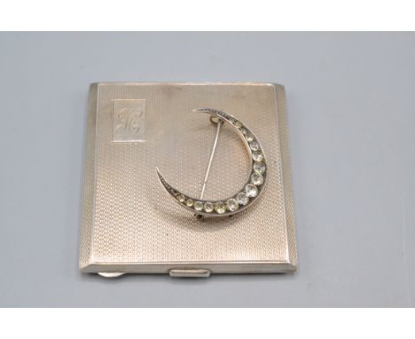 A silver compact and a silver crescent brooch.