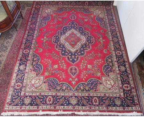 A Tabriz carpet, North West Persia, the red field with a polychrome lobed pole medallion and floral sprays, within an indigo 