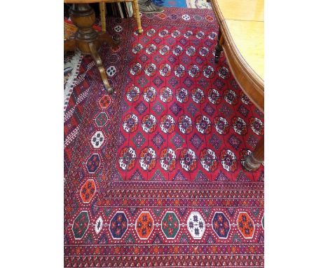 A Pakistan carpet, the madder field with seventeen rows of six medallions, within an octagonal sunburst gul border, 309 x 271