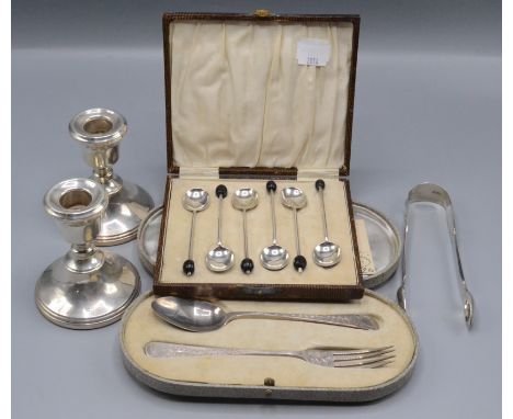 A pair of silver candlesticks, height 9cm, a cased set of six silver spoons, a pair of silver sugar tongs and a cased spoon a