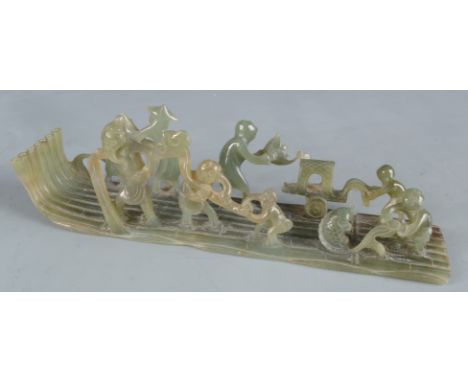 A Chinese mottled green jade carving of a tree log raft, 20th century, with elderly and youthful figures fishing for carp and