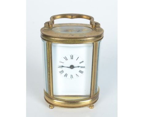 A brass oval carriage clock, the white enamelled dial with roman numerals, height of case 8.5cm, width 6.5cm, depth 4.7cm.