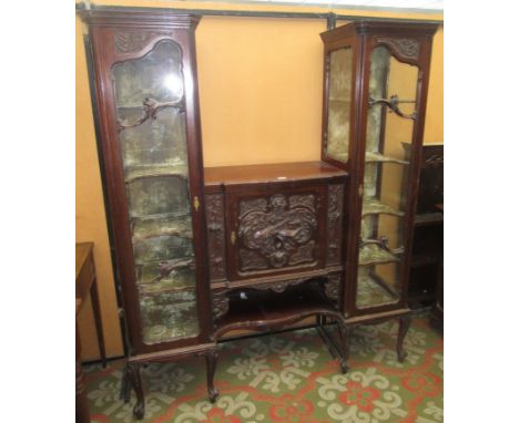 An Edwardian mahogany display cabinet, the central cupboard door carved with musical instruments and foliage above a single s