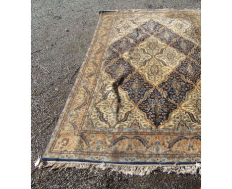 A Persian design carpet, with Islamic script cartouche to one end, the ivory and indigo trellis field enclosing small medalli