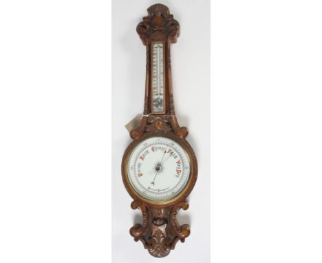 A Victorian carved walnut aneroid barometer, with a mercury filled thermometer above a 19cm white enamel dial, height 86cm. C