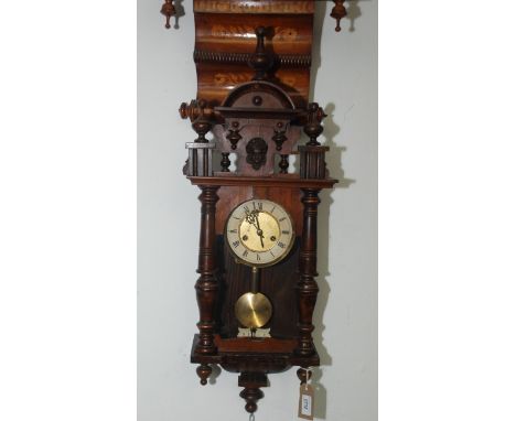 A Vienna walnut wall clock, 19th century, with three finials flanking a central portrait mask, the 13.2cm dial with roman num