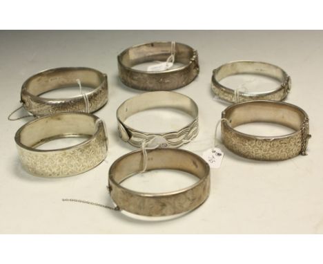 A silver bangle, hinged, chased and engraved; others, similar (7)