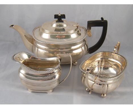 A three piece silver teaset, barge shaped with gadrooned rim, the teapot and sugar basin on ball feet by Charles Stuart Harri