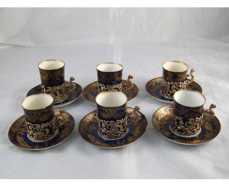 A set of six late Victorian gilt blue porcelain coffee cups and saucers, the cups with silver holders by William Comyns, Birm