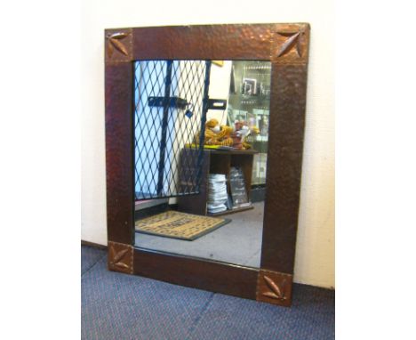 A copper framed Arts and Crafts mirror with hammered finish , embossed leaf quadrants and original plate. 56x72cm. 