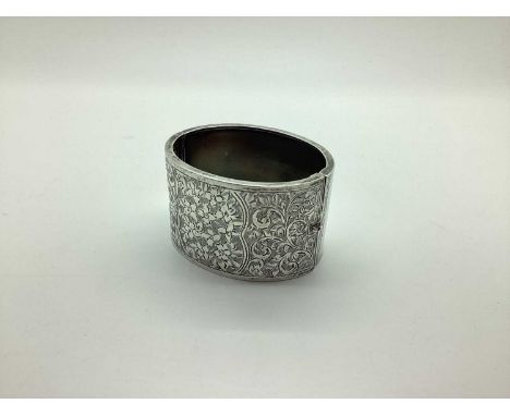 A Victorian Style Hallmarked Silver Wide Hinged Bangle, foliate leaf scroll engraved to the front, hinged to snap clasp (dent