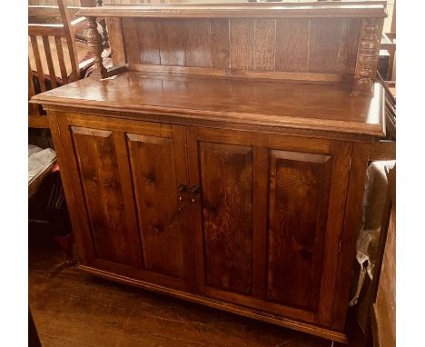 A 20th century oak low linen press, quarter gallery mounted with a moulded edge shelf on turned supports, on twin panel cupbo