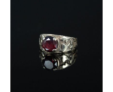 A 9ct gold ring set with single garnet with ornate embossed and engraved shoulders, size K 1/2 