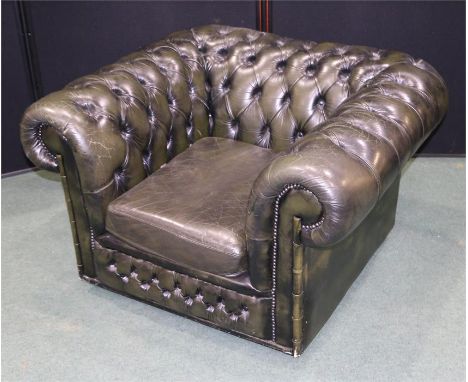 Leather button back armchair, in green leather with scroll arms above the sprung seat