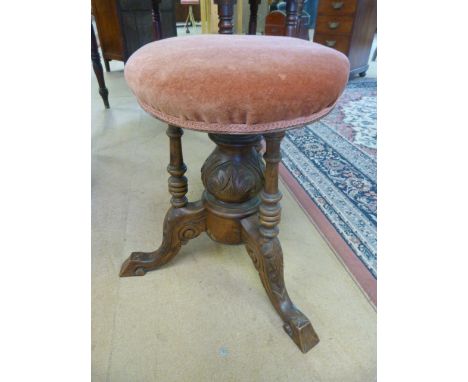 Revolving mahogany piano stool with three turned wooden supports leading down to a baluster base with tripod feet