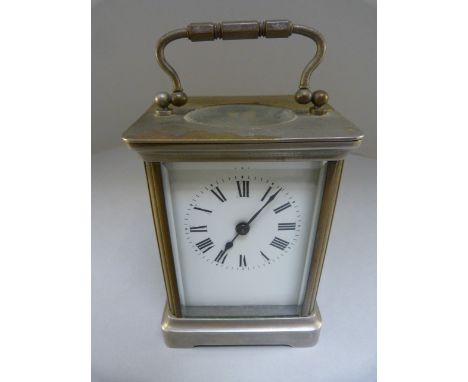 Brass cased carriage clock with 5 panels of bevelled glass. The chapters are Roman Numerals on a white enamelled unmarked fac