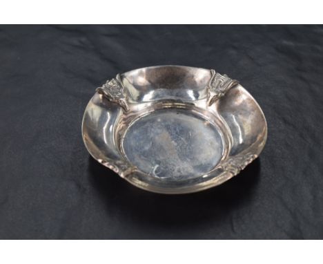 An interesting 900 grade white metal pin dish, the rim embossed with stylised rams head and axe motifs, marked 900, 8.5cm, 36