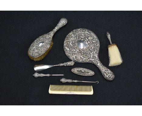 An Edwardian silver backed hand mirror, of traditional design embossed with foliate scrolls and birds, marks for Birmingham 1