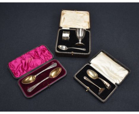 A cased George V silver christening set, comprising egg cup, napkin ring and spoon, each with engraved initials GE, marks for