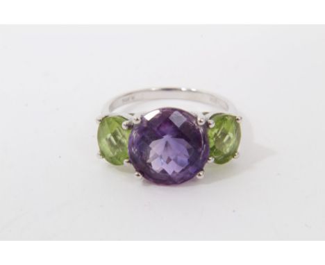 White gold (14k) amethyst and peridot three stone dress ring with a central round faceted cut amethyst flanked by an oval cut