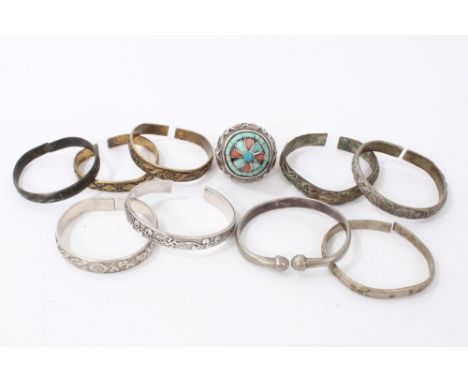 Group of Chinese and Eastern white metal and brass bangles, together with a large Thai/Eastern dress ring inset with coral an